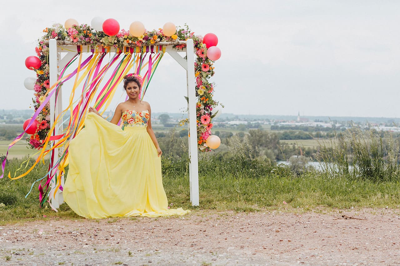 Braut vor toll dekorierter Hochzeitslocation mit Blumengirlande aus Steckschaum