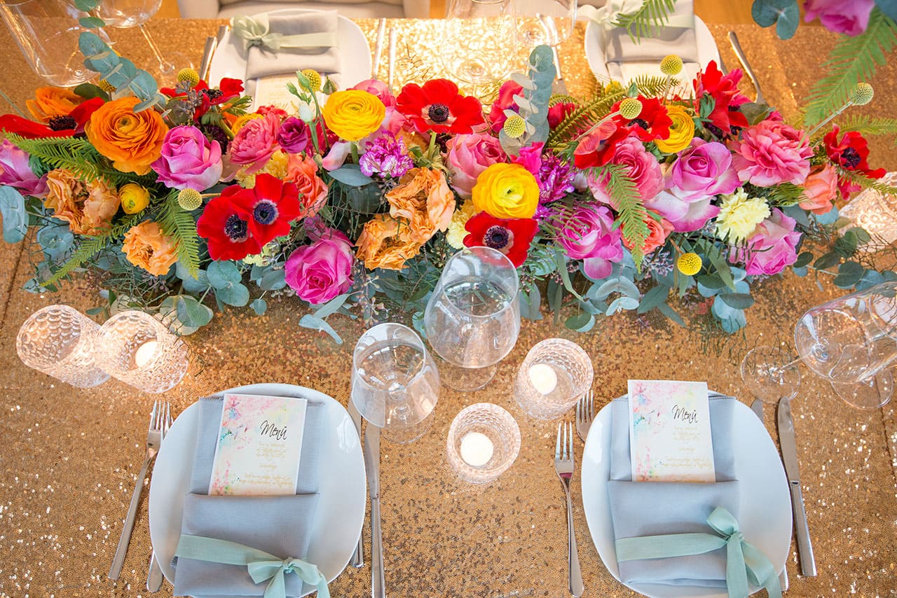 Tischdekoration mit Steckschaum aus bunten Blumen in Orange, Rot, Gelb und Pink