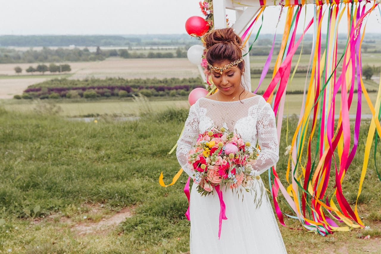 Braut mit buntem Brautstrauß in toll dekorierter Hochzeitslocation 