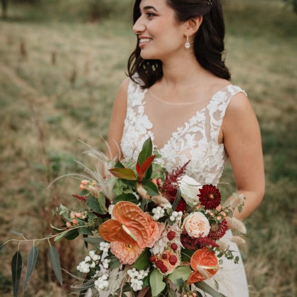 Hochzeitsblumen - Braut mit Brautstrauß in rot orange weiß