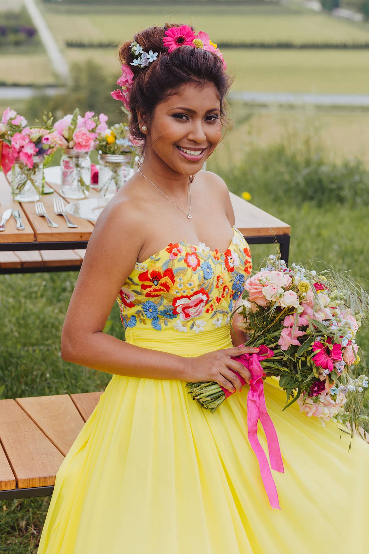 Braut im bunten Hochzeitskleid mit Blumenschmuck und Brautstrauß