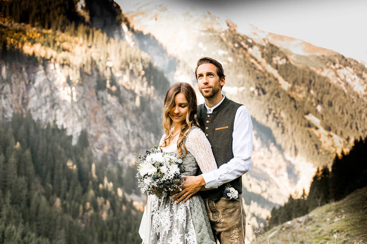 Brautpaar in den Bergen mit Dirndl und Lederhose