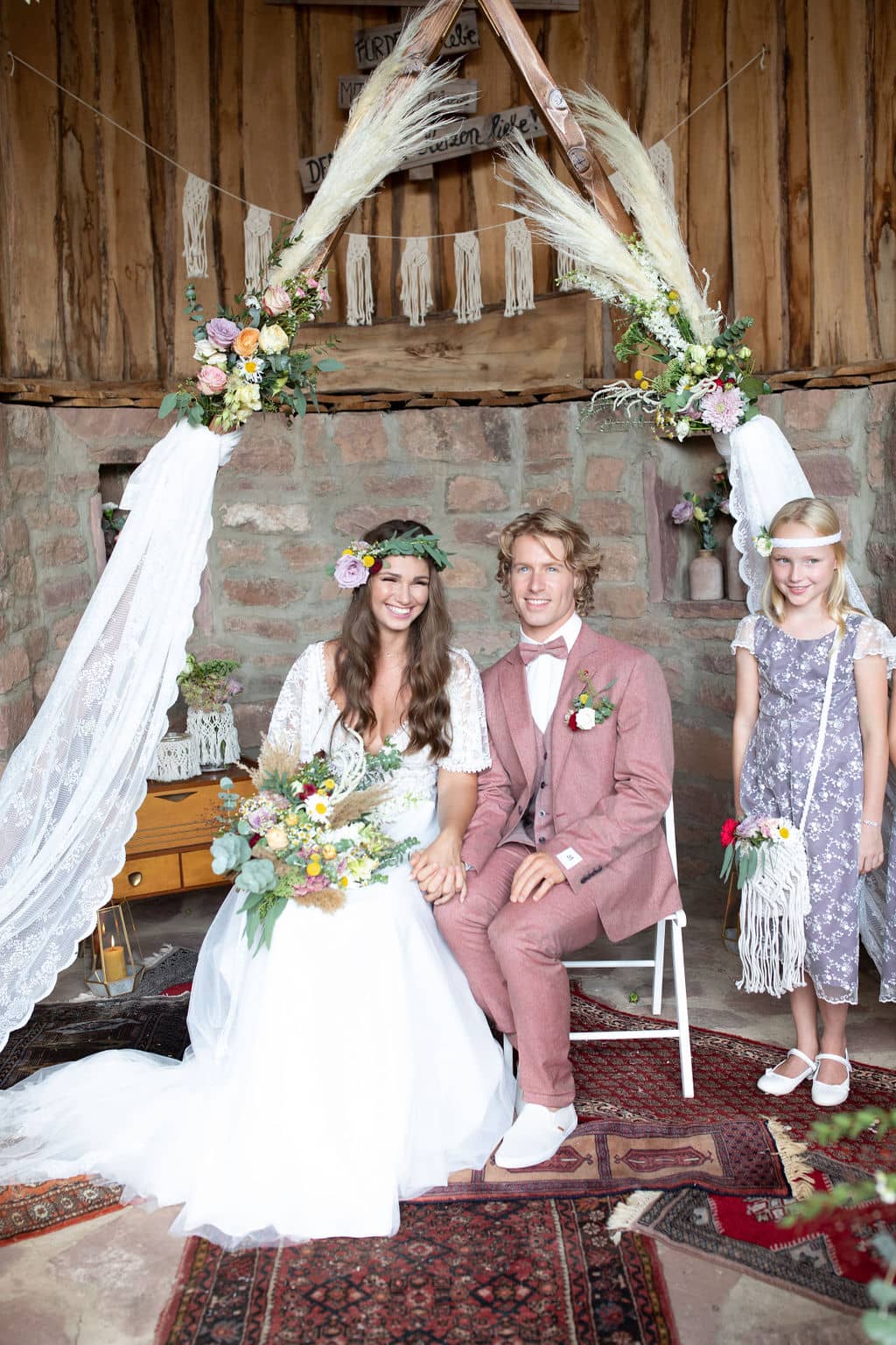 BOHO Vintage Hochzeit - Brautpaar mit Brautstrauß bei wunderschöner Raumdeko mit Blumen
